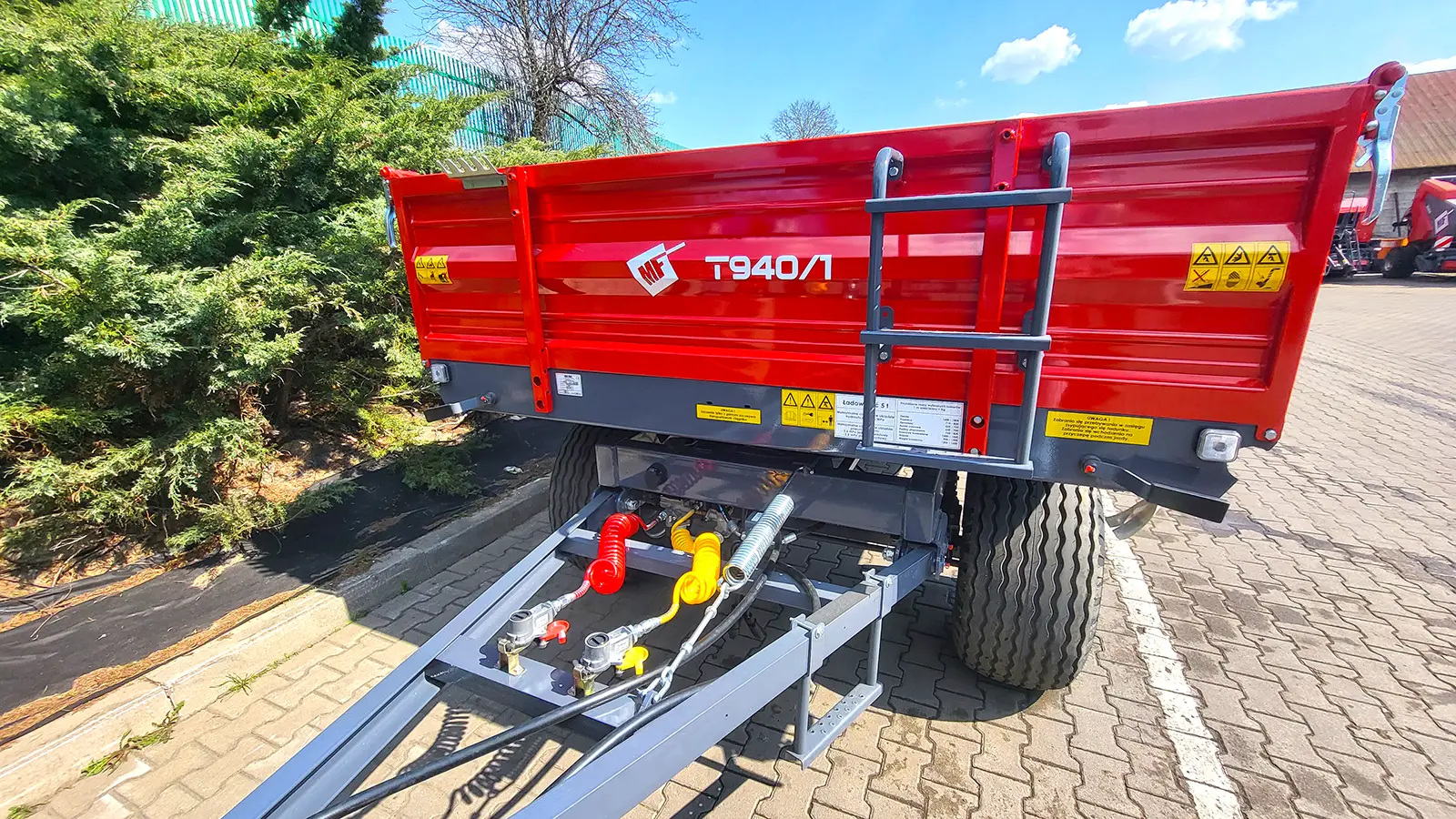 Widok z przodu czerwonej przyczepy rolniczej wywrotki dwuosiowej Metal-Fach T940/1 – 5 ton z podłączeniami hydraulicznymi i pneumatycznymi